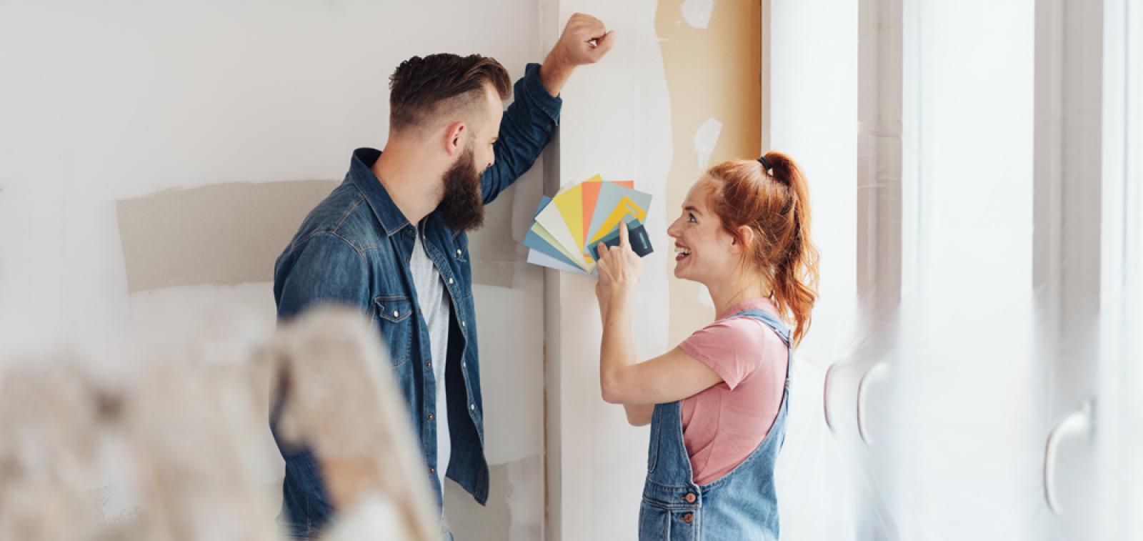 Two people looking at a colour swatch fan in front of a plain wall