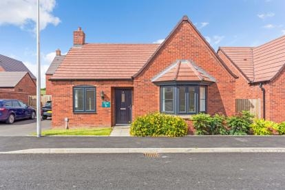 A red bricked bungalow with bay window at the front of the property
